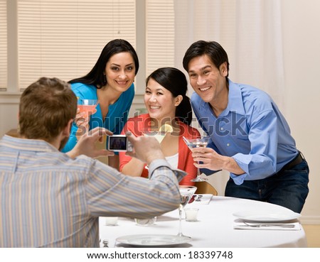 Couples holding martini cocktails and posing for photograph at dinner party