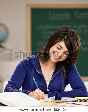 Determined student with text books doing homework in school classroom