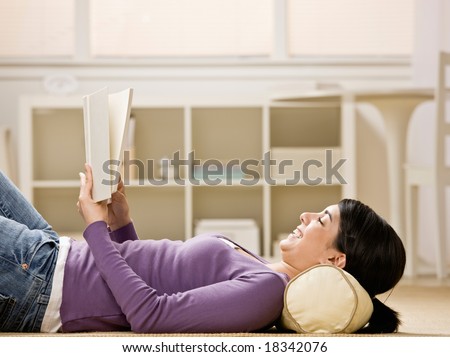 Relaxed woman laying on floor enjoying reading a book