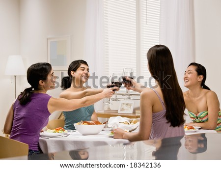Friends toasting with red wine at dinner party