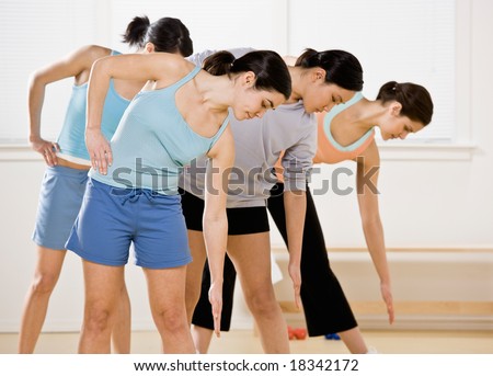 Women bending and stretching during exercise class in health club