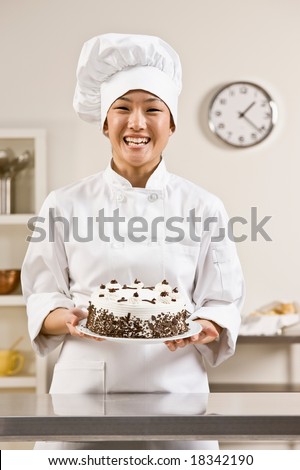 Bakery chef in toque and chef?s whites proudly holding birthday cake