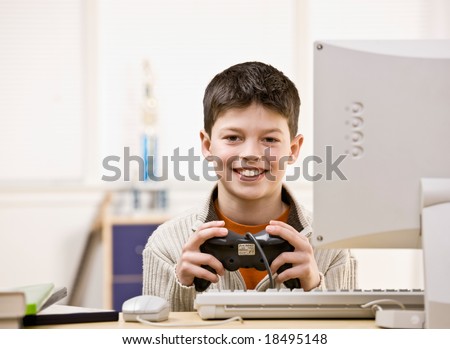 Boy holding video game controller having fun playing video game on computer