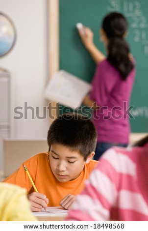 Concentrating student writing in notebook in school classroom