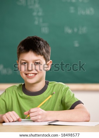 Happy student writing in notebook in school classroom