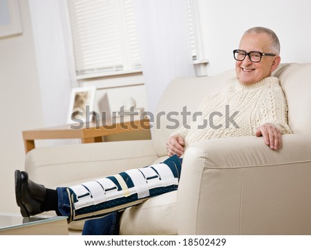 Disabled man with leg brace sitting on sofa in livingroom