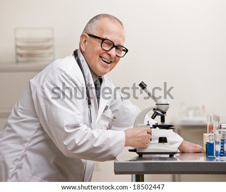 Research scientist in lab coat with microscope in laboratory
