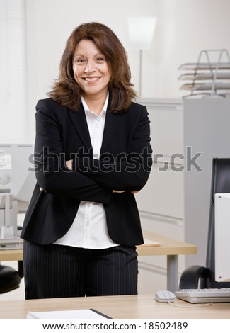 Confident businesswoman standing at desk in office