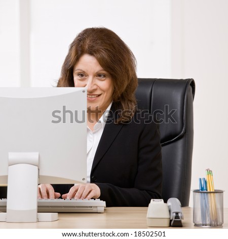 Confident businesswoman typing on computer at desk