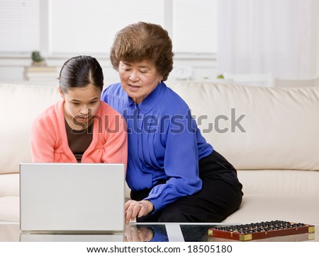 Granddaughter listening to grandmother explain how to use laptop