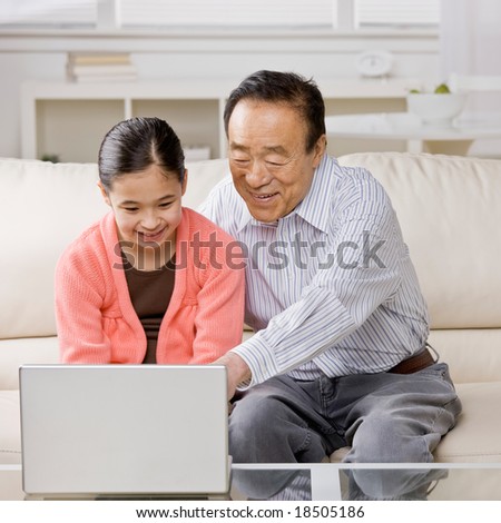 Granddaughter listening to grandfather explain how to use laptop