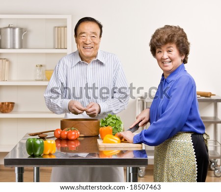 Helpful man preparing wholesome salad with wife in kitchen for dinner