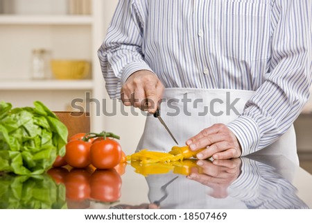 Helpful man preparing wholesome salad in kitchen for dinner