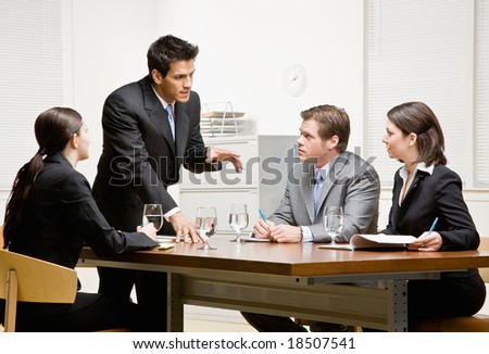 Co-workers listening to supervisor explain problem in conference room