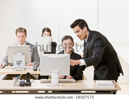 Co-worker listening to supervisor explain problem on computer