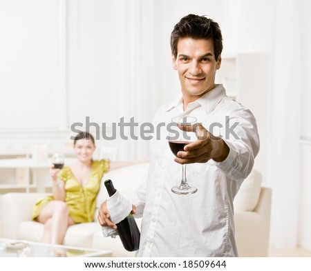 Confident man offering glass of red wine