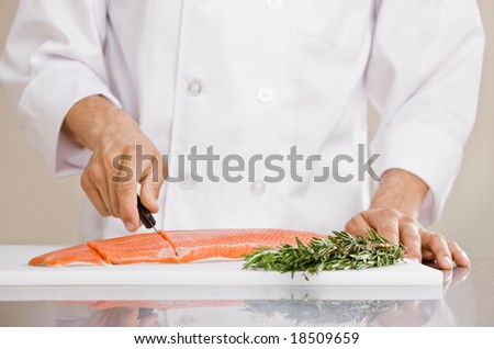 Chef in chef?s whites slicing raw salmon to prepare for meal