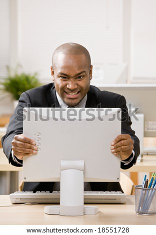 Frustrated, angry businessman grimacing at computer monitor