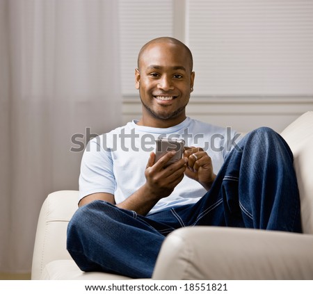 Relaxed man using electronic organizer in livingroom