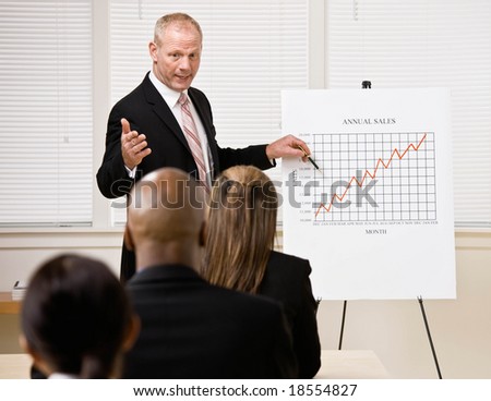 Confident businessman explaining financial analysis chart to co-workers