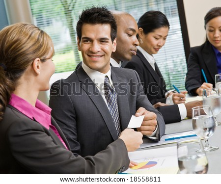 Businessman offering business card to female colleague in conference room