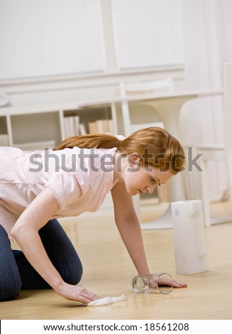 Frustrated housewife kneeling and wiping up spilled water from floor
