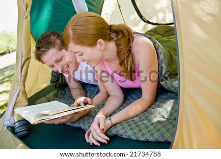 Couple laying in tent reading book