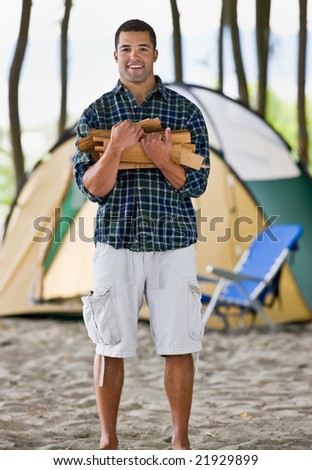 Man carrying wood at campsite