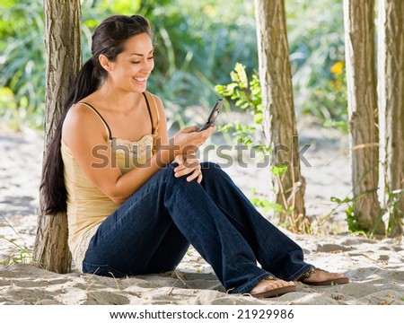 Woman text messaging on cell phone at beach