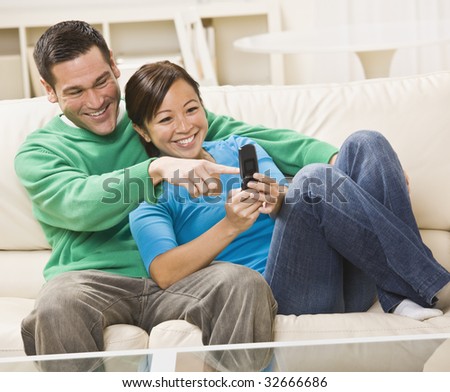 Mixed race couple laughing and looking at a cell phone together. horizontal