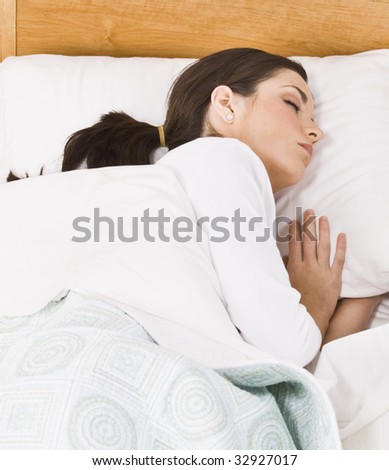 Attractive brunette woman sleeping on her side. Vertically framed shot.