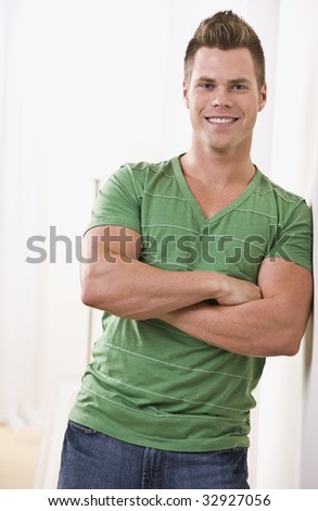 Attractive man leaning on wall in green t-shirt. vertical