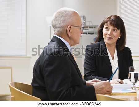 Business meeting with senior male and attractive female at desk. Horizontal