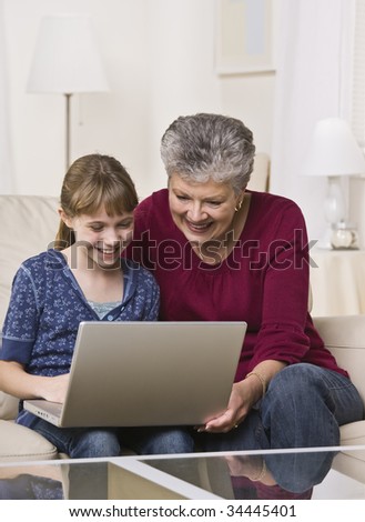 A grandmother and granddaughter use a laptop computer together at home.  Vertically framed shot.