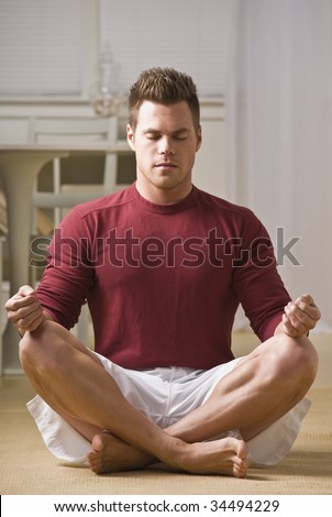 Attractive male in lotus position with eyes closed and hands on knees. Vertical