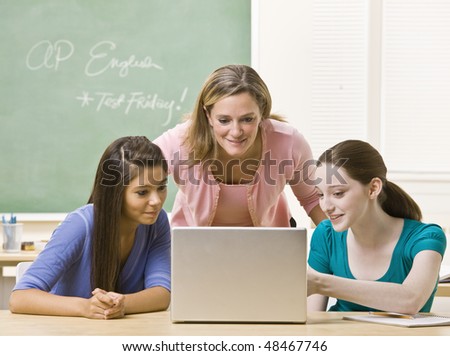 Teacher helping students on laptop