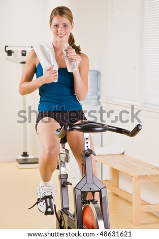 Woman riding stationary bicycle in health club