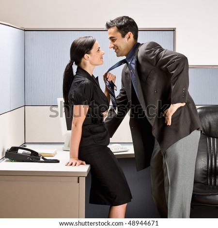 Co-workers kissing in office cubicle
