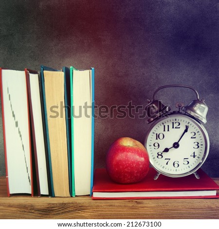 Still life with school books and apple against clean black blackboard on background