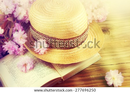 Straw hat, book and spring flowers over wooden table. Relaxation or vacation concept