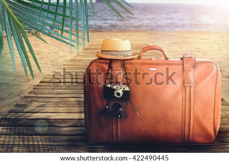 Concept of summer traveling with old suitcase on blur beach background.