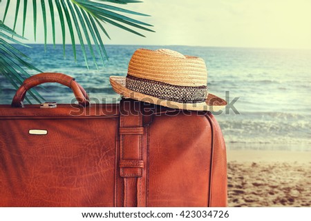 Concept of summer traveling with old suitcase on blur beach background.
