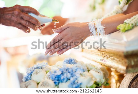 hand of a bride receiving holy water from elders in thai culture