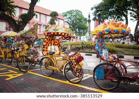 Trishaw decorated with colorful flowers waiting for customer in Malacca city that designated UNESCO world heritage site, Malaysia. Select focus at Center trishaw