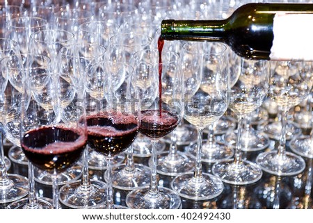 Pouring red wine into many glass. waiters poured into glasses of wine for night event party. Selective focus