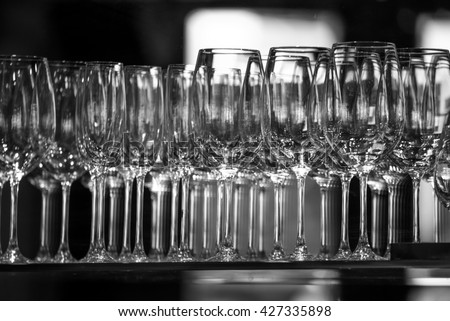 Rows of empty wine glasses on the showcase, black and white photography. Lots of wine glasses, Wine glasses lined, Wine glasses in row on bar  on light grey background