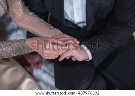 Bride putting a wedding ring on groom's finger. Wedding rings, engagement ring on the finger of the groom