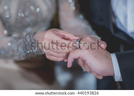 Hands of the groom and bride is wearing a ring on the finger on the day of the wedding ceremony. Gold, symbol, religion, love. bride\'s hand putting a wedding ring on the groom\'s finger. Close up