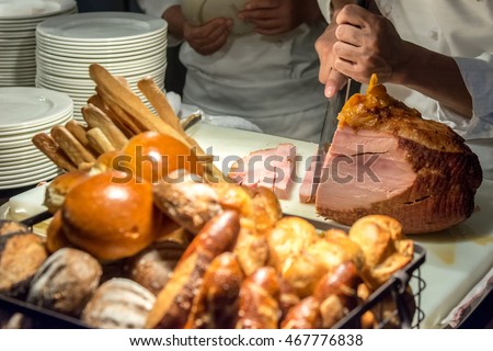 Chef Carving Slices Of Roast ham show in night event party. food in European style display in night party event. Select focus at movement cutting ham by chef