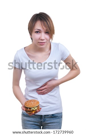 Portrait of girl with hamburger in the hands and strong stomach-ache isolated on white